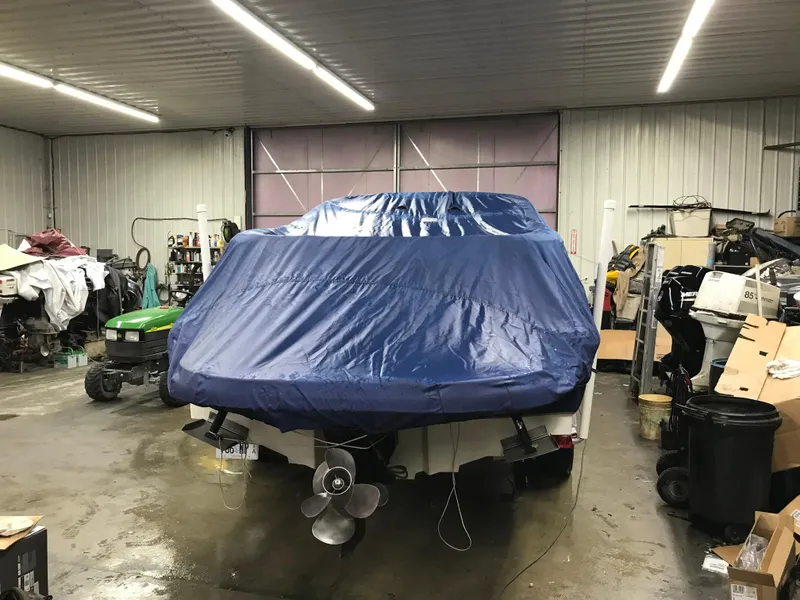Slide: The Image of 2004 Sea Ray 240 Sundeck boat covered in a blue tarp in a storage facility. - 23