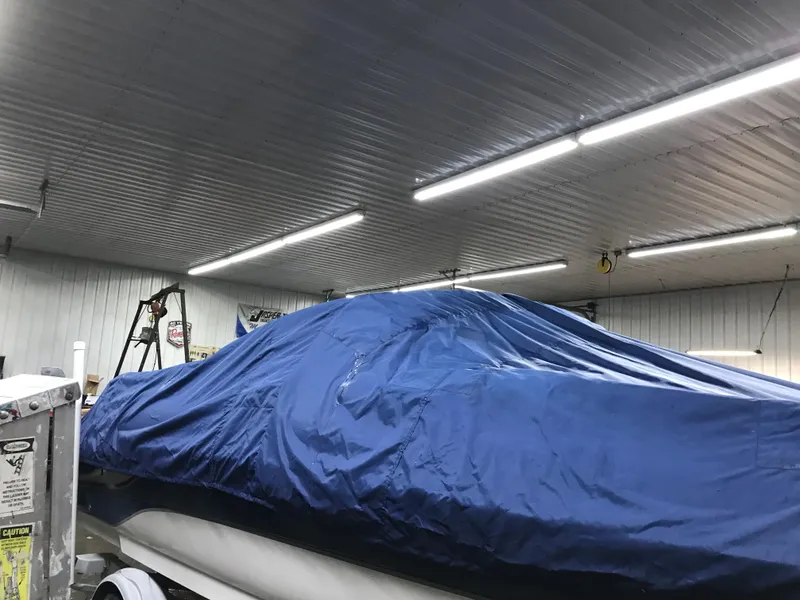 Slide: The Image of 2004 Sea Ray 240 Sundeck covered in blue tarp inside a well-lit garage. - 24