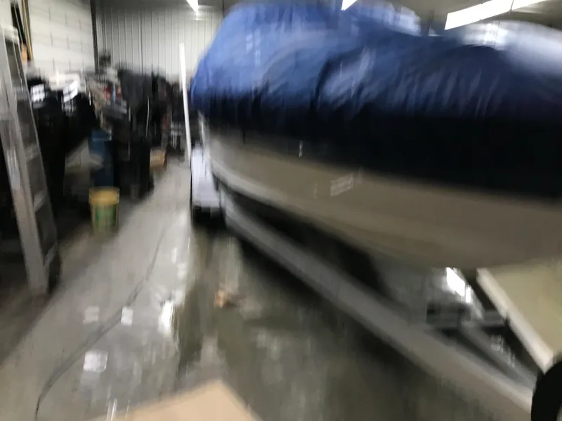 Slide: The Image of 2004 Sea Ray 240 Sundeck boat covered in blue tarp, stored indoors. - 25