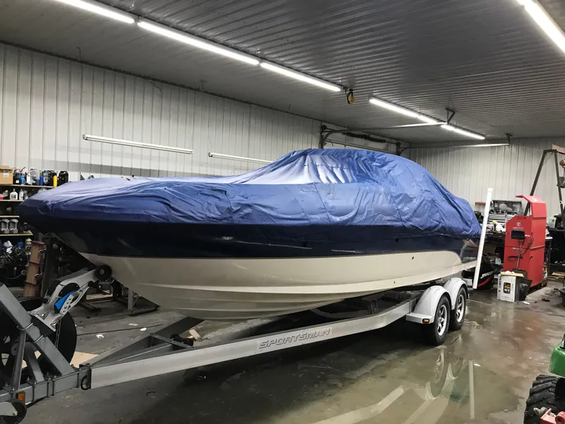 Slide: The Image of 2004 Sea Ray 240 Sundeck boat with blue cover on trailer in garage. - 26