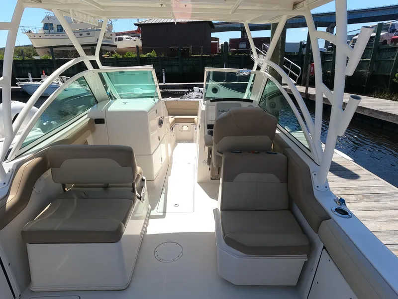 Slide: The Image of 2017 Sailfish 245 DC boat interior at dock, featuring seating and helm. - 11