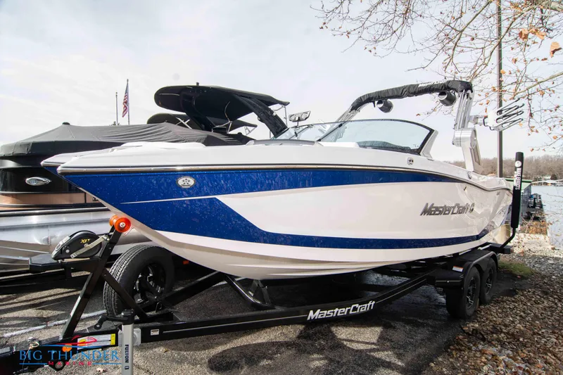 Slide: The Image of 2024 MasterCraft X22 boat on a trailer by the lake. - 0