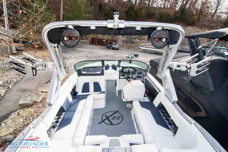 Slide: The Image of 2024 MasterCraft X22 boat interior with white and blue seating, advanced dashboard, and wakeboard racks. - 13