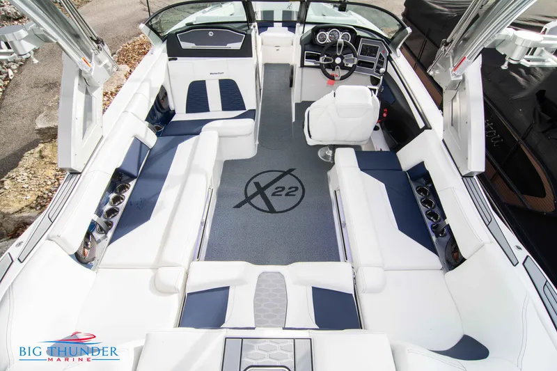 Slide: The Image of 2024 MasterCraft X22 boat interior with white and blue seating, steering console, and Big Thunder Marine logo. - 14