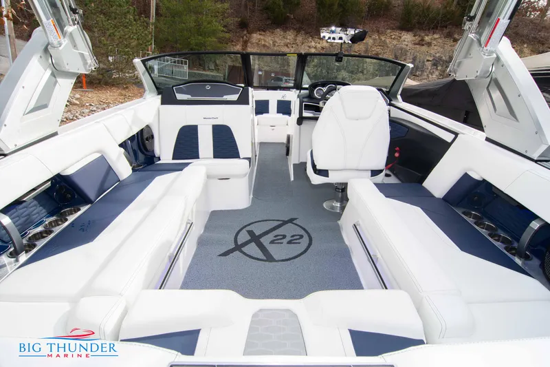 Slide: The Image of 2024 MasterCraft X22 boat interior with white and blue seating, Big Thunder Marine logo. - 16