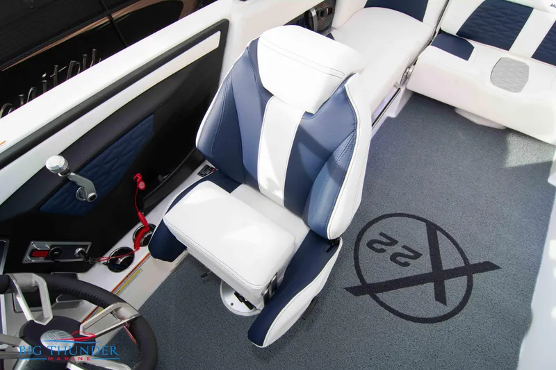 Slide: The Image of 2024 MasterCraft X22 boat interior with captain's chair and logo on carpet. - 36