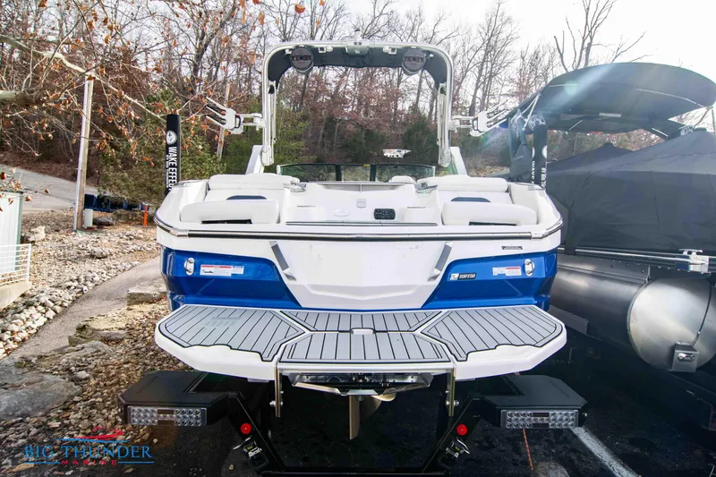 Slide: The Image of 2024 MasterCraft X22 boat, rear view, docked, blue and white color scheme. - 4