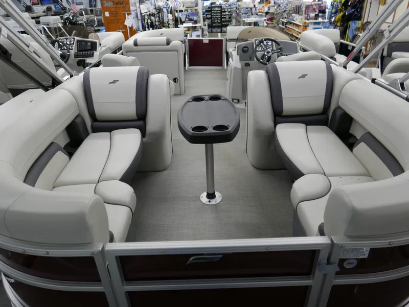 Slide: The Image of 2024 Starcraft EX 22 R pontoon boat interior with plush seating and central table. - 19