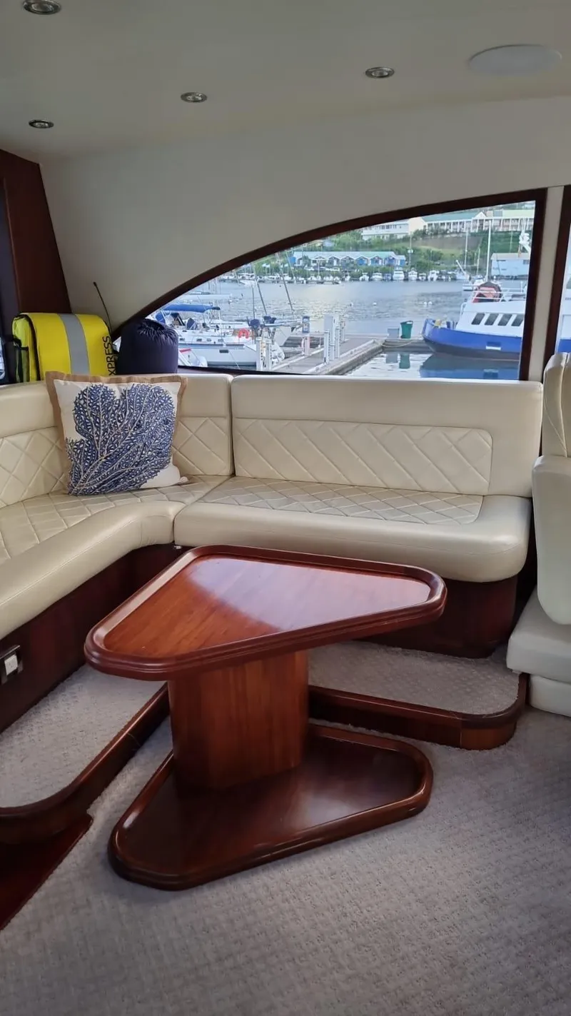 Slide: The Image of Interior of a 2009 Bertram 700 Enclosed yacht with leather seating and wooden table. - 14
