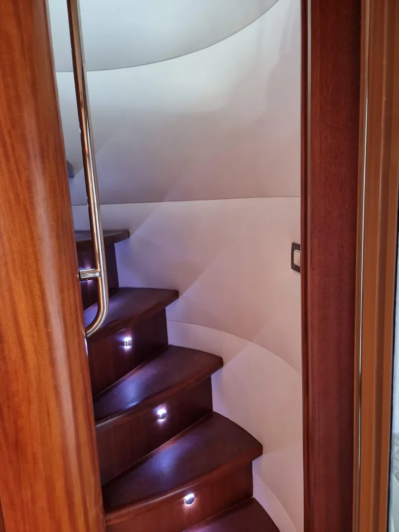Slide: The Image of Interior staircase of 2009 Bertram 700 Enclosed yacht with wooden steps and LED lighting. - 16
