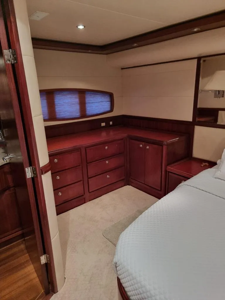 Slide: The Image of 2009 Bertram 700 Enclosed yacht bedroom with wooden cabinetry and cozy lighting. - 19