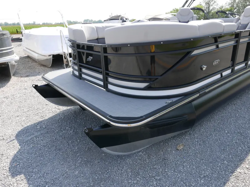 Slide: The Image of 2024 Starcraft SLS 3 Q DH pontoon boat with sleek black design on gravel surface. - 2