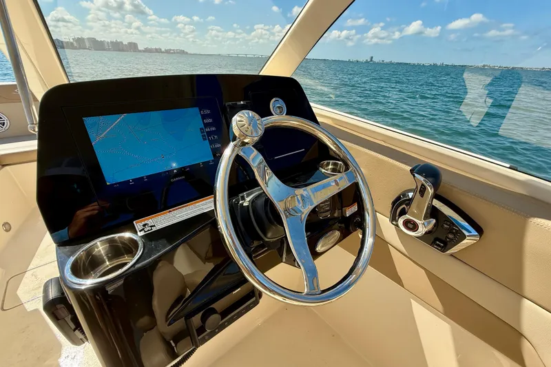 Slide: The Image of 2024 Scout 240 Dorado boat helm with steering wheel and navigation display. - 15