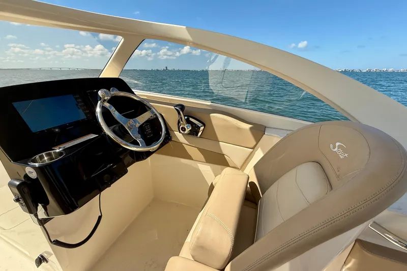 Slide: The Image of 2024 Scout 240 Dorado boat interior with steering wheel, dashboard, and water view. - 16