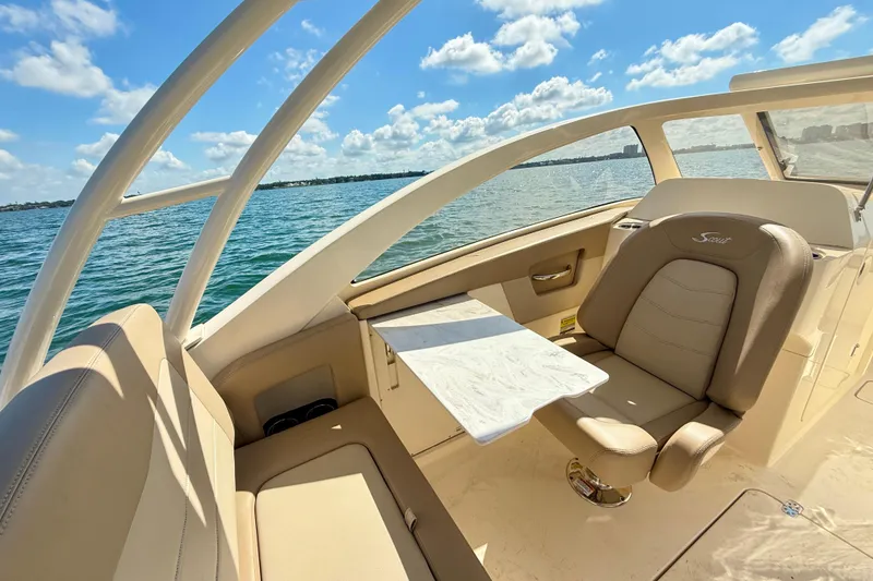 Slide: The Image of 2024 Scout 240 Dorado boat interior with luxurious seating and table, overlooking serene waters. - 18