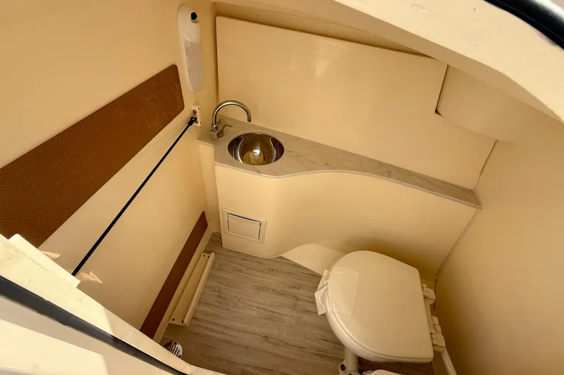 Slide: The Image of 2024 Scout 240 Dorado boat interior with compact bathroom, sink, and toilet. - 23