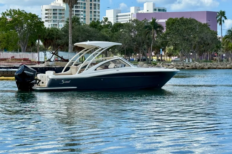 Slide: The Image of 2024 Scout 240 Dorado boat on calm water with cityscape background. - 6
