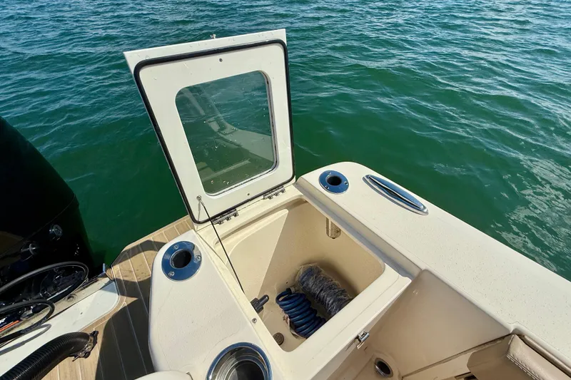 Slide: The Image of 2024 Scout 240 Dorado boat with open storage compartment on calm water. - 8