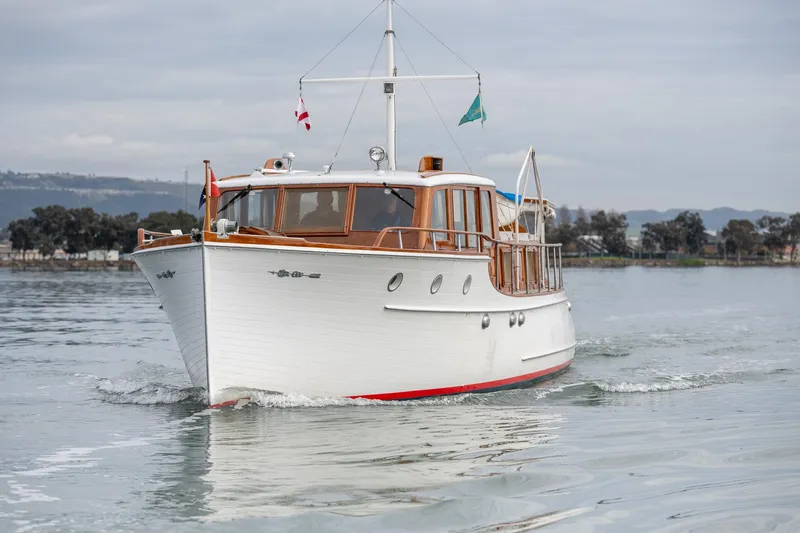 Slide: The Image of 1939 Stephens Brothers Bridgedeck Cruiser on calm water, showcasing classic wooden design. - 2
