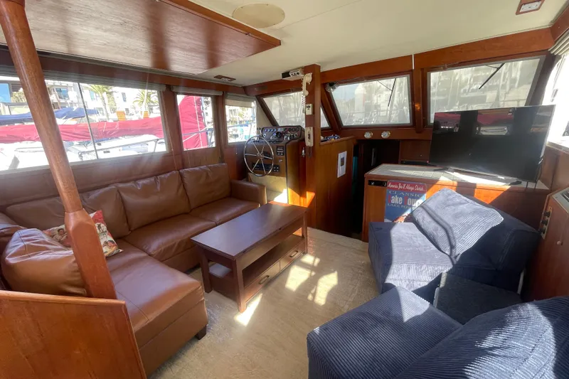 Slide: The Image of 1975 Uniflite Aft Cabin interior with leather seating and wooden helm, docked at marina. - 20