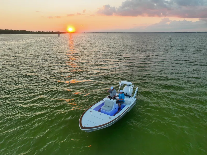 Slide: The Image of 2024 Xcelerator Boatworks 17 Flats on serene water at sunset. - 10