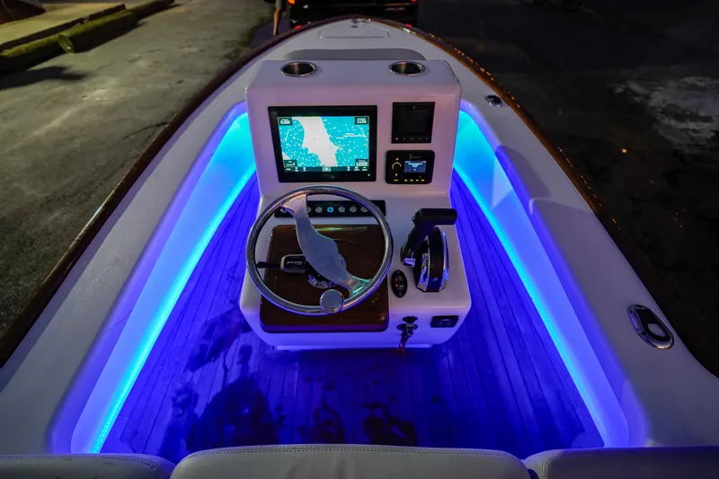 Slide: The Image of 2024 Xcelerator Boatworks 17 Flats console with illuminated blue LED lights at night. - 12