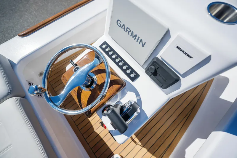 Slide: The Image of 2024 Xcelerator Boatworks 17 Flats console with Garmin and Mercury controls, featuring a sleek steering wheel. - 17