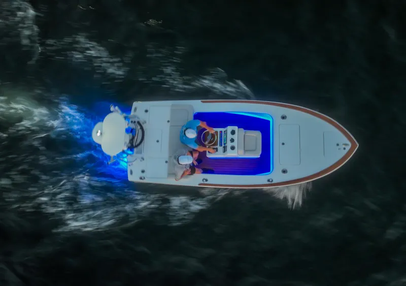 Slide: The Image of 2024 Xcelerator Boatworks 17 Flats boat cruising at night with blue underwater lights. - 2