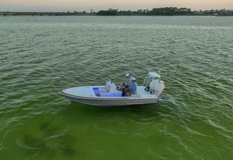 Slide: The Image of 2024 Xcelerator Boatworks 17 Flats on calm water, two people onboard, scenic background. - 4