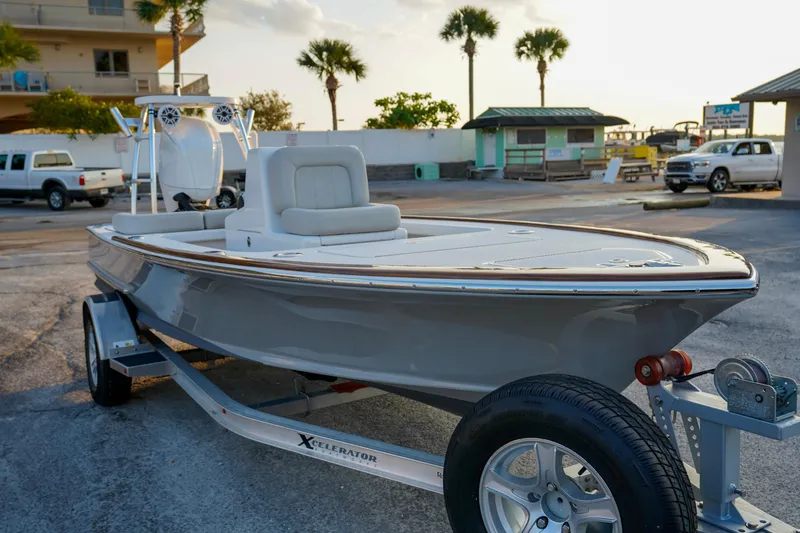 Slide: The Image of 2024 Xcelerator Boatworks 17 Flats boat on trailer at marina, palm trees in background. - 5