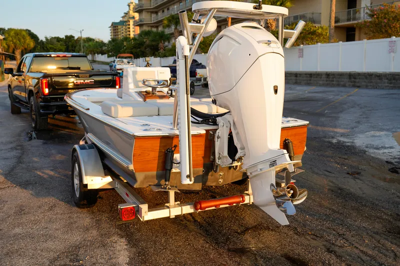 Slide: The Image of 2024 Xcelerator Boatworks 17 Flats on trailer, attached to a GMC truck, in a parking lot. - 6