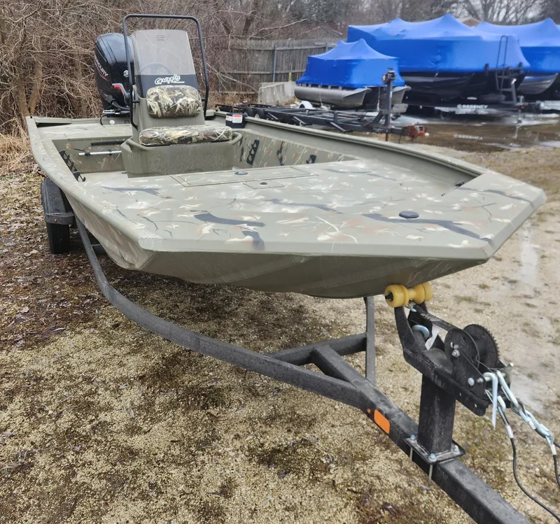 Slide: The Image of 2024 Tracker Grizzly 1860 CC boat on a trailer, camo design, parked outdoors. - 2