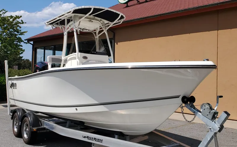 Slide: The Image of 2024 Mako 214 CC boat on trailer, parked outside a building. - 2