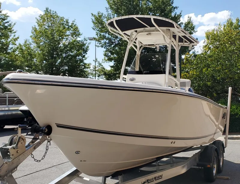 Slide: The Image of 2024 Mako 214 CC boat on trailer, parked outdoors with trees in background. - 3