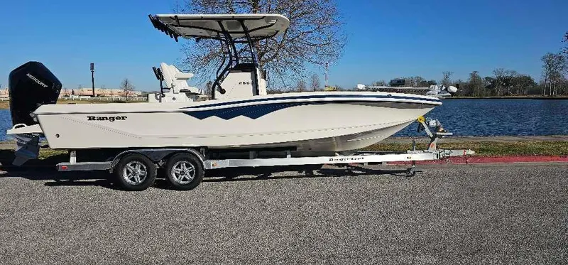 Slide: The Image of 2024 Ranger 2660 Bay boat on a trailer by a lake. - 1