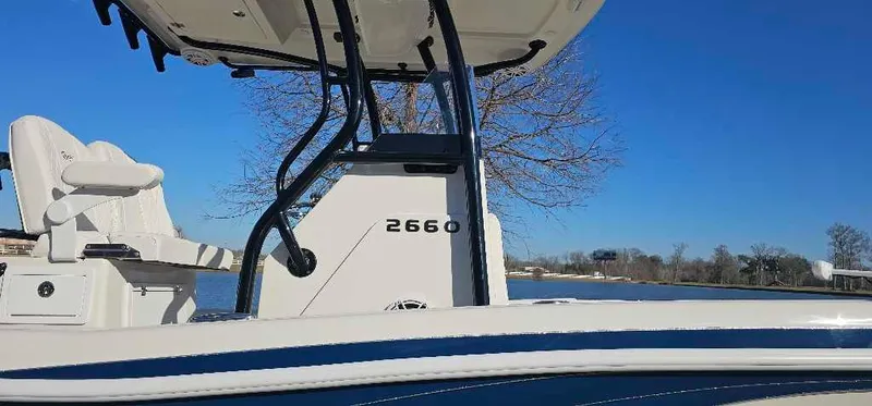 Slide: The Image of 2024 Ranger 2660 Bay boat with white seating and blue accents on a sunny day. - 2