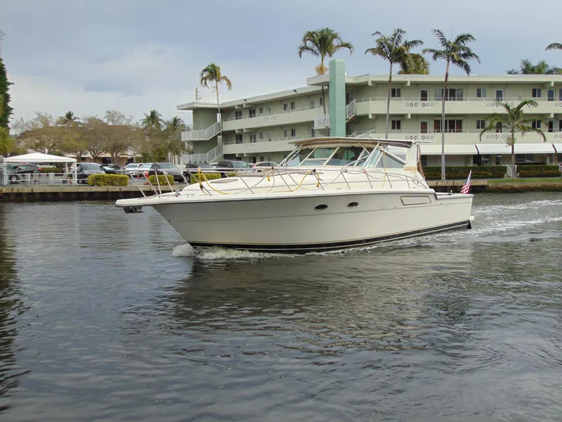 Slide: The Image of 1996 Tiara Yachts 4300 Open cruising near waterfront buildings. - 1