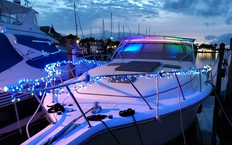 Slide: The Image of 1996 Tiara Yachts 4300 Open decorated with blue lights at dusk in a marina. - 14