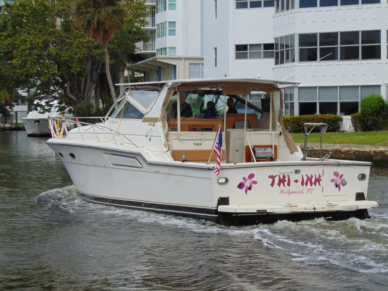Slide: The Image of 1996 Tiara Yachts 4300 Open cruising in a canal near modern buildings. - 3