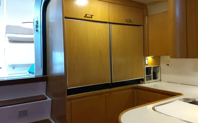 Slide: The Image of 1996 Tiara Yachts 4300 Open kitchen with wooden cabinets and built-in appliances. - 7