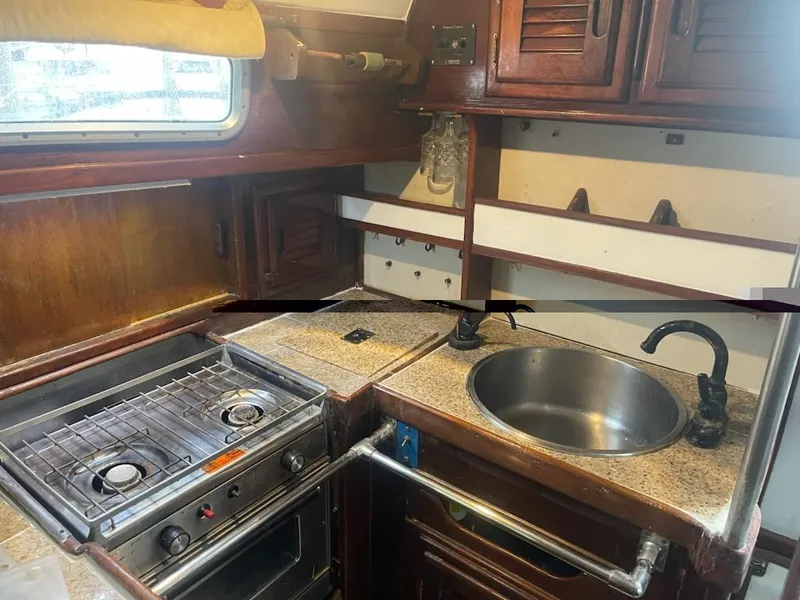 Slide: The Image of 1981 Allied Mistress Mk III boat kitchen with stove, sink, and wooden cabinets. - 5