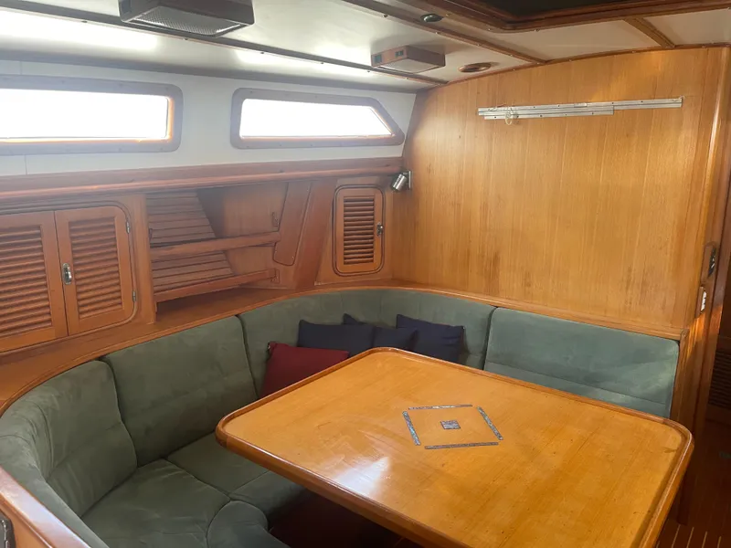 Slide: The Image of Interior of 1995 Passport 47 AC Plan B sailboat with wooden dining area and cushioned seating. - 19