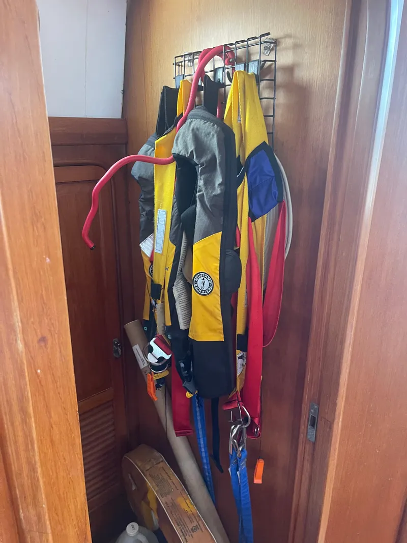 Slide: The Image of Life jackets hanging in a wooden closet on a 1995 Passport 47 AC Plan B sailboat. - 22