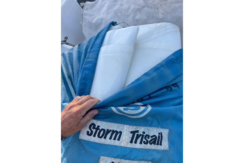 Slide: The Image of Hand holding a blue sail labeled "Storm Trisail" on a 1995 Passport 47 AC Plan B. - 49