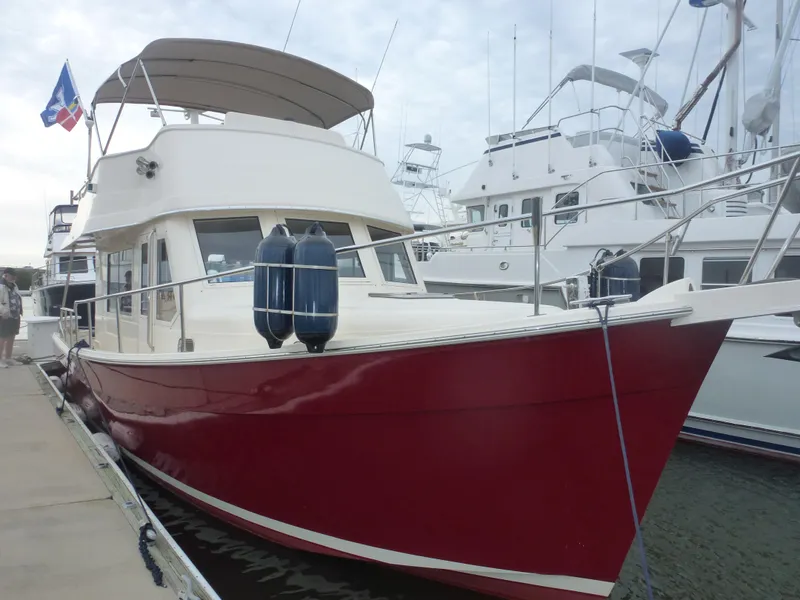 Slide: The Image of 2005 Mainship 34 Trawler with red hull docked at marina. - 0
