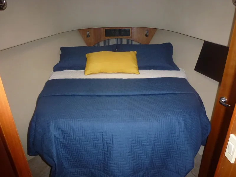 Slide: The Image of 2005 Mainship 34 Trawler bedroom with blue bedding and yellow pillow. - 19