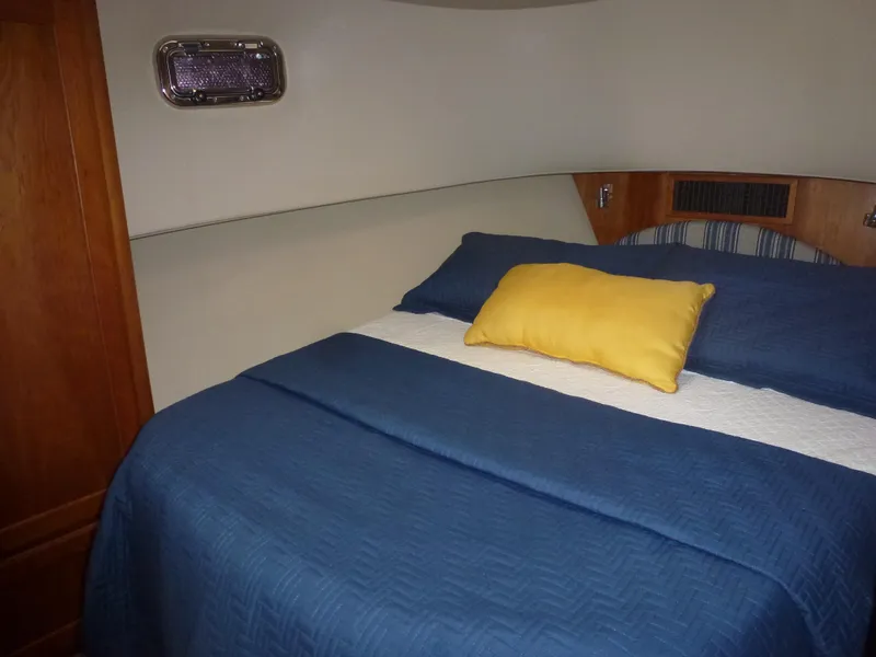 Slide: The Image of Mainship 34 Trawler 2005 bedroom with blue bedding and yellow pillow. - 20