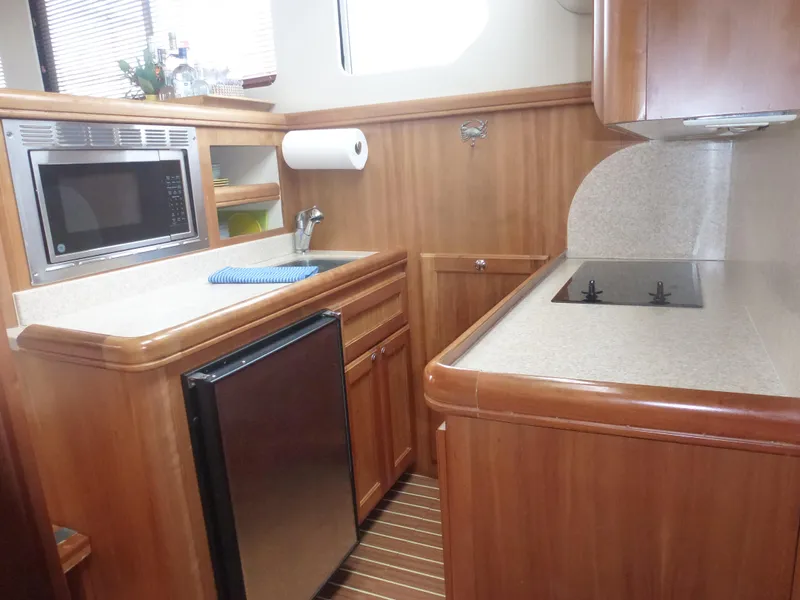 Slide: The Image of 2005 Mainship 34 Trawler kitchen with microwave, sink, fridge, and stove. - 24