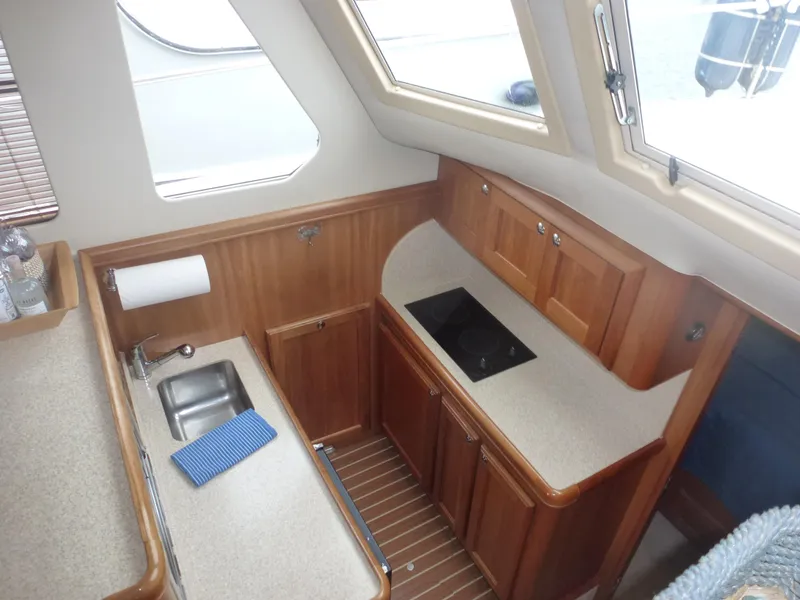 Slide: The Image of 2005 Mainship 34 Trawler kitchen with sink, stove, and wooden cabinetry. - 26