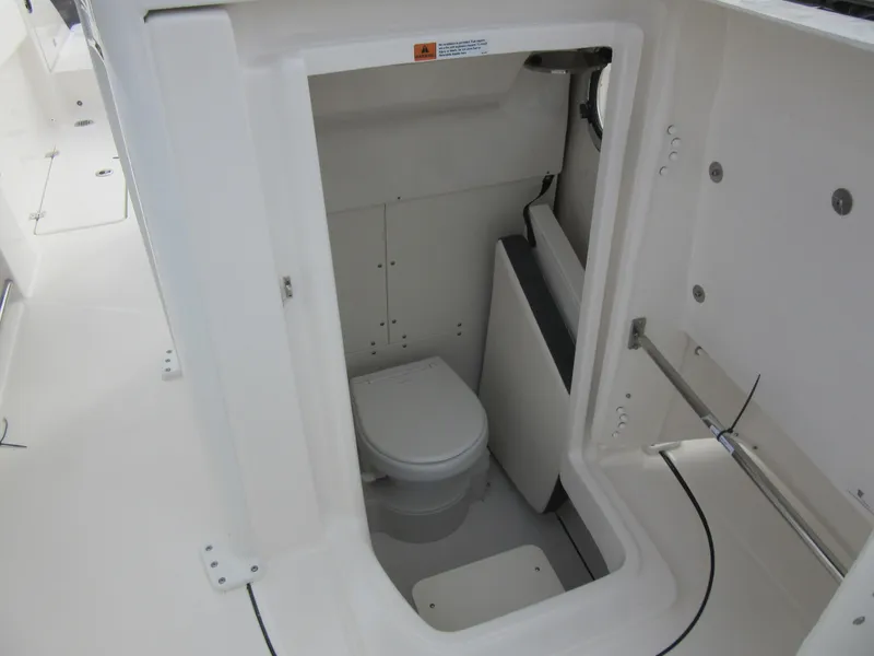 Slide: The Image of 2024 Robalo R250 Center Console boat interior with a compact marine toilet. - 20